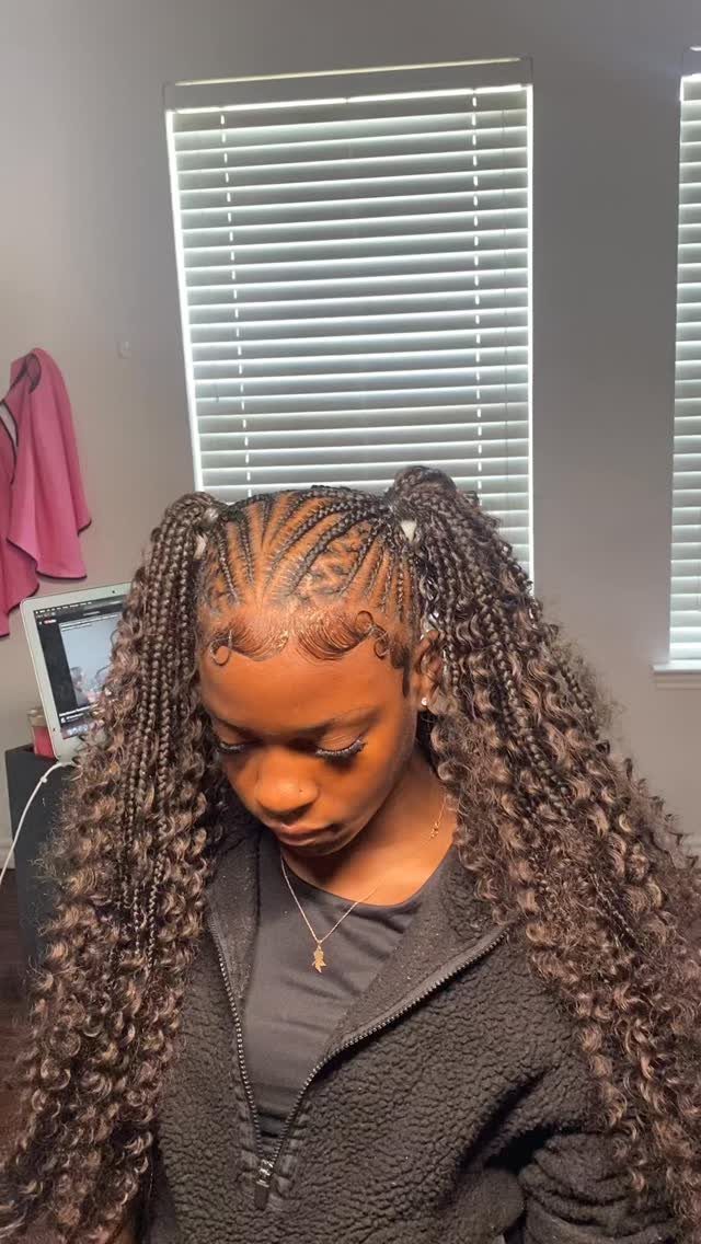 Woman with cornrows styled into two high, curly braided pigtails and laid edges.