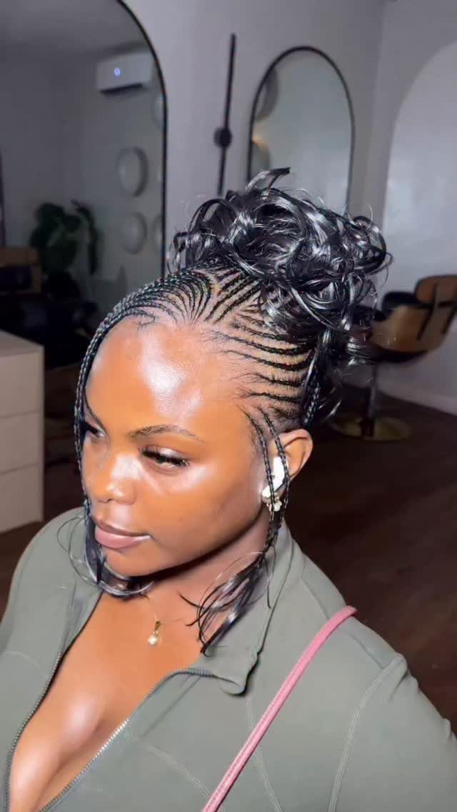 Woman with cornrow braids styled into a high curly bun wearing olive green.