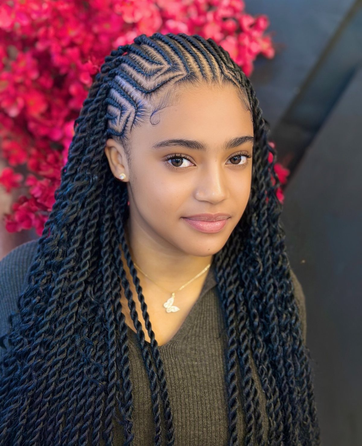 Young woman with intricate geometric cornrow braids and long twisted black hair.
