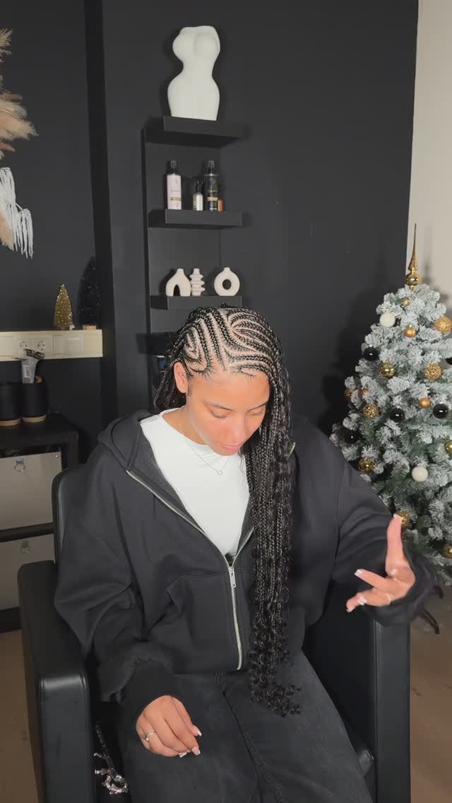 Woman with Fulani style cornrow braids wearing a black hoodie in a room.