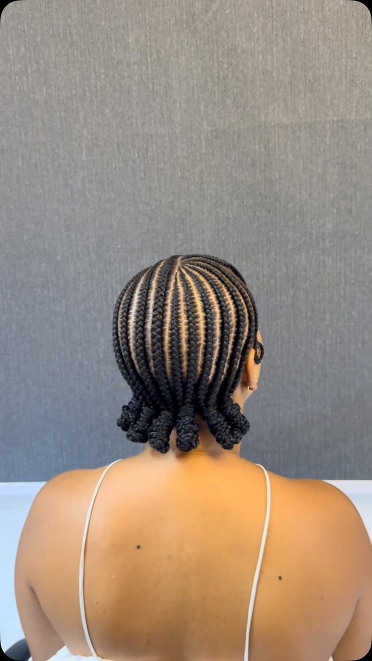 Back view of a person with black cornrow braids ending in small buns.