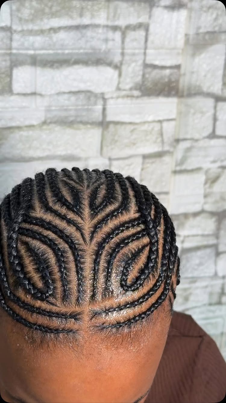 Intricate cornrow braids styled in a symmetrical leaf pattern on a person's head.