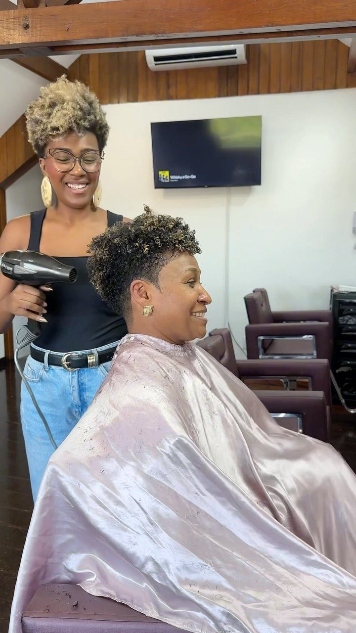 Woman with a short curly pixie cut getting her hair dried in a salon
