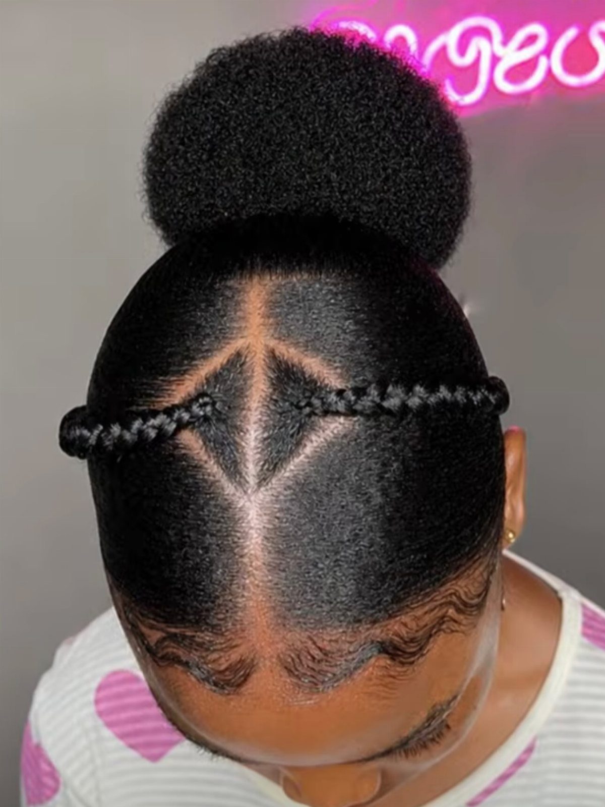High afro puff updo with a geometric diamond part and horizontal braid.