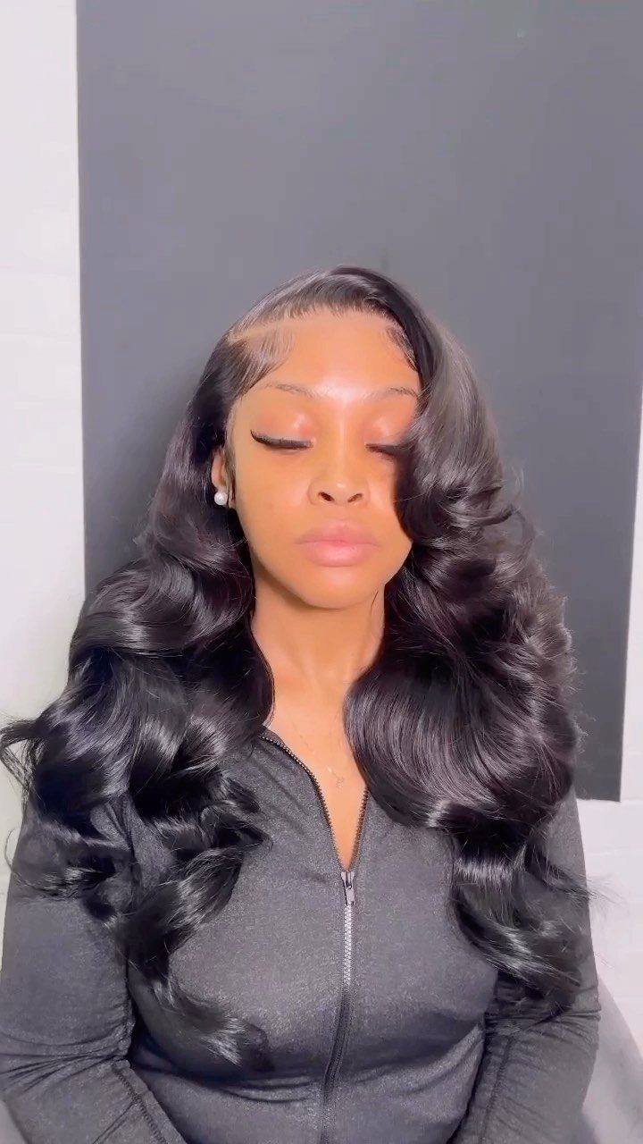 Woman with long, voluminous black hair styled in polished waves against grey background