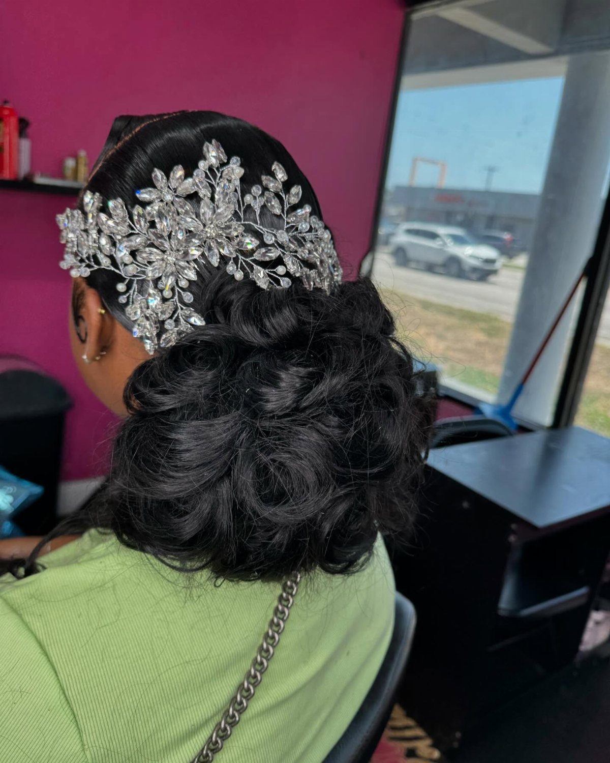 Curly low bun hairstyle adorned with a large silver rhinestone hairpiece