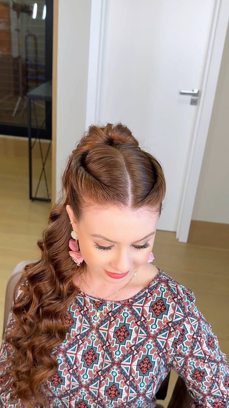 Woman with reddish-brown curly hair styled in a half-updo with a twisted knot.
