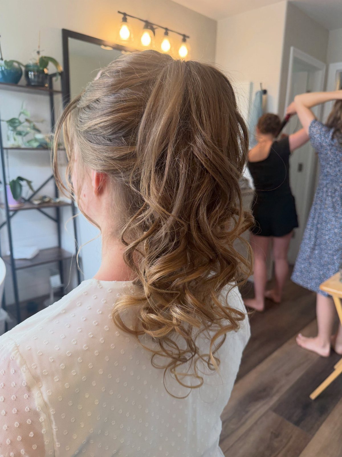 Woman with light brown hair in a romantic half-updo with soft curls.