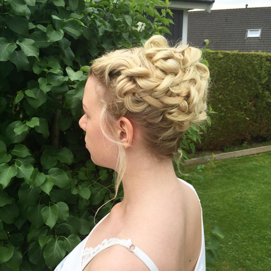 Blonde woman with a voluminous curly updo and braids in a garden setting