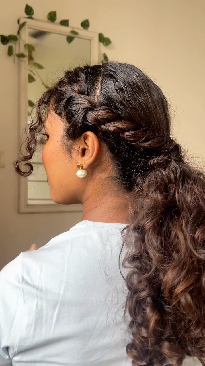 Woman with dark brown curly hair in a twisted low ponytail hairstyle.