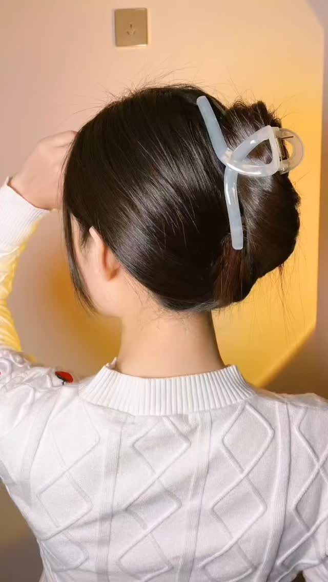 Dark hair styled in a bun secured with a white claw clip