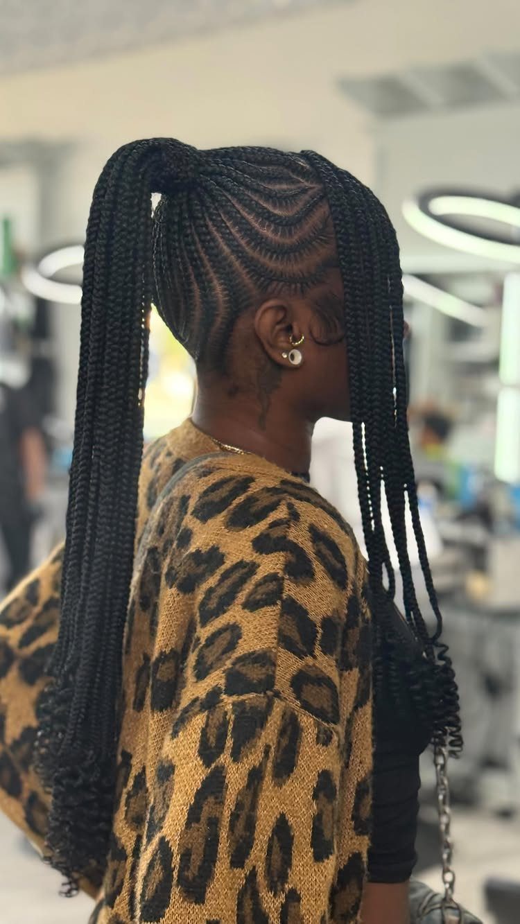 Person with long black braided hair styled in a high ponytail and leopard print cardigan.