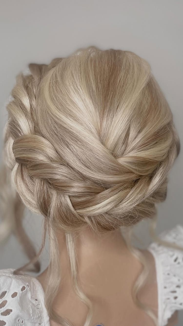 Intricate blonde updo hairstyle with twists and braids on long hair.