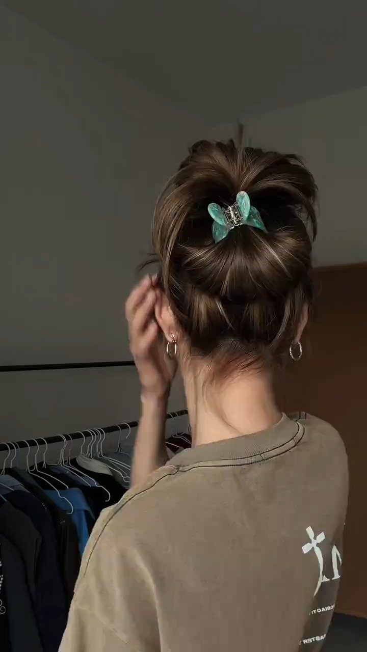 Brown hair styled in a high bun secured with a teal claw clip.