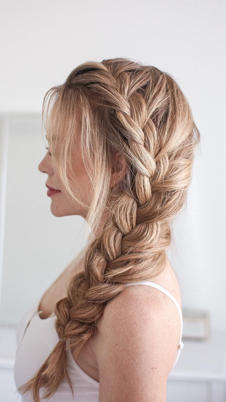 Blonde woman with a thick, voluminous side braid draped over her shoulder.