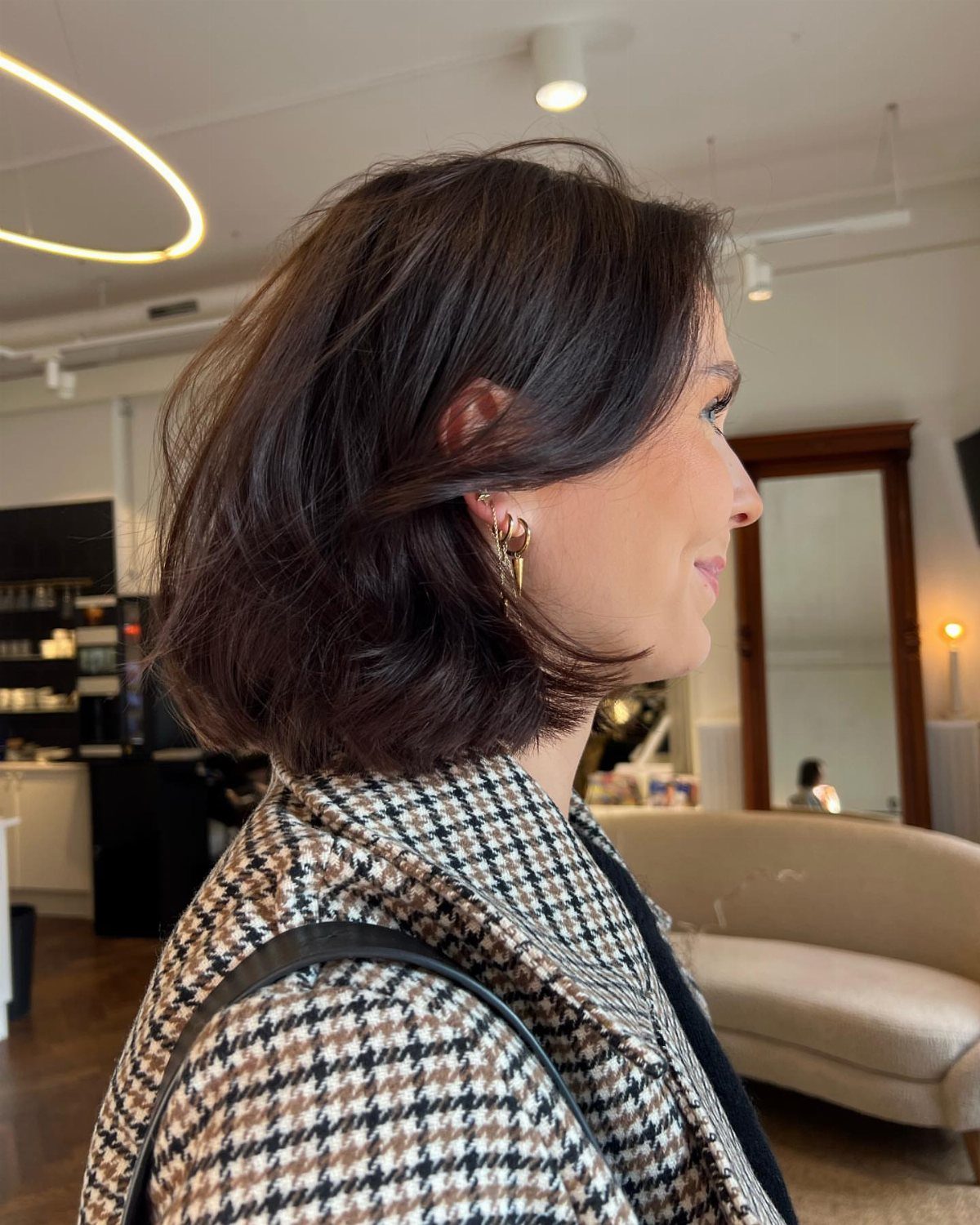 Woman with a side-parted dark brown bob hairstyle wearing a houndstooth blazer.
