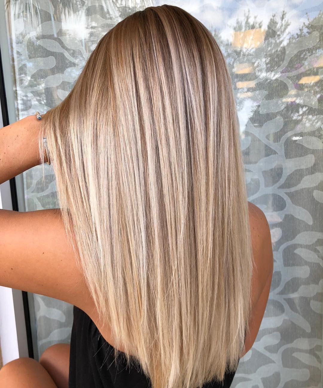 Long straight blonde hair with dark roots seen from the back.