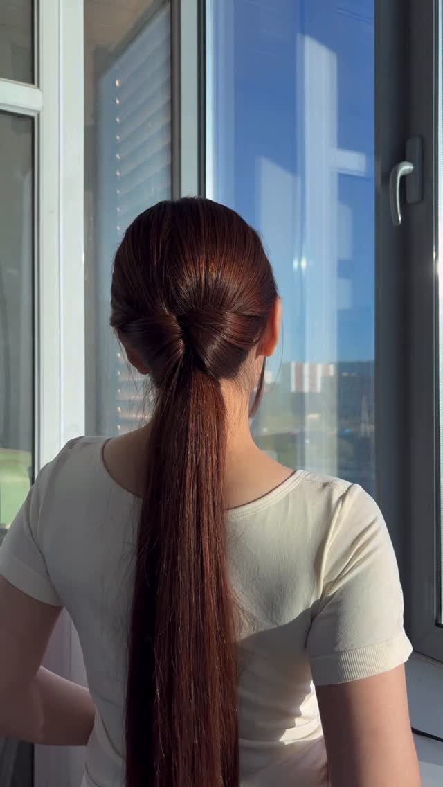 Woman with long brown hair in a ponytail with a twisted base detail.
