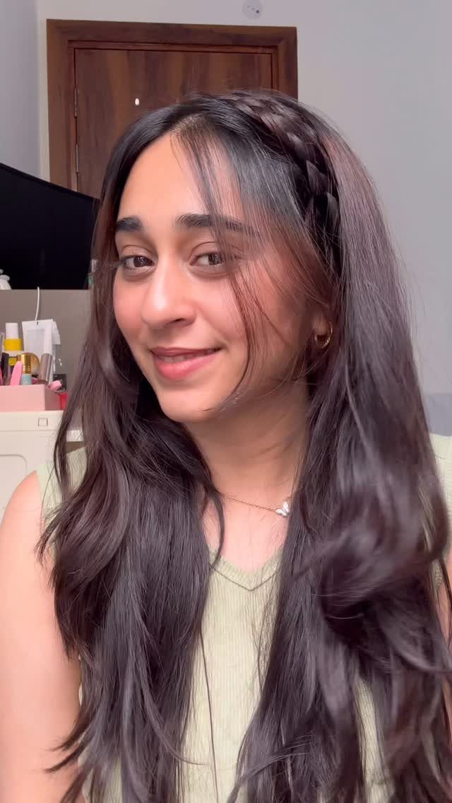 Woman with long dark wavy hair featuring a braided headband hairstyle.