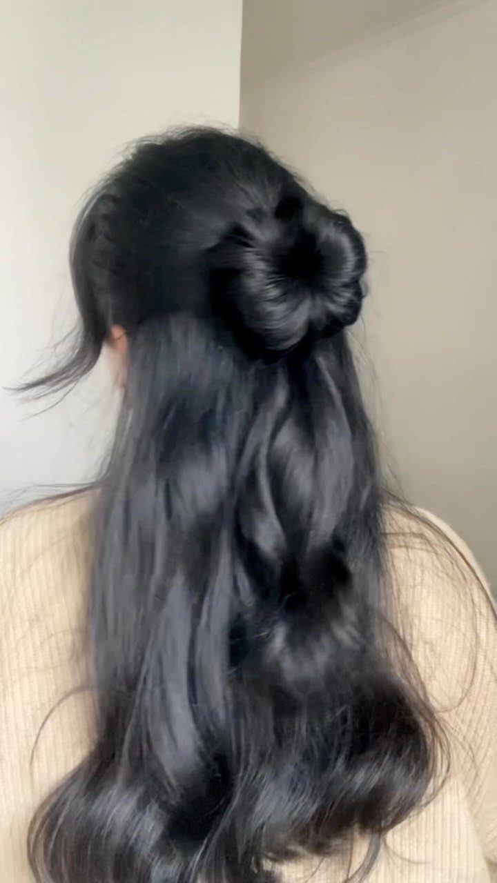 Long wavy black hair styled in a half-up bun from the back view