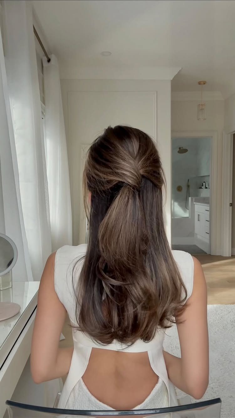 Woman with long brown hair in a half-up twisted hairstyle wearing white dress