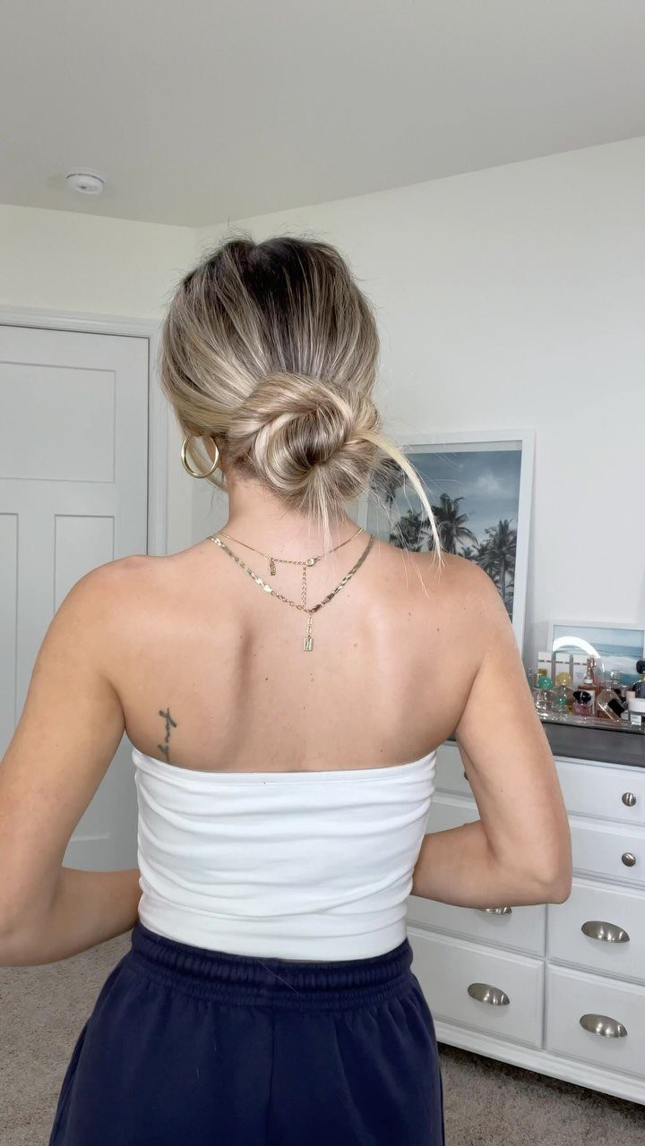 Woman with blonde hair styled in a loose low bun from behind.