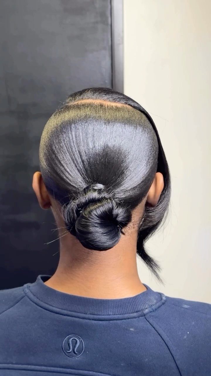 Sleek black hair styled into a polished low bun with a side-swept section.