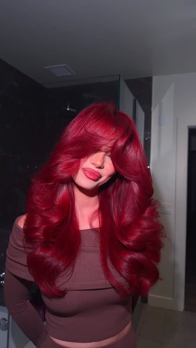 8 Deep Red Hair Dye Ideas for Every Cut and Texture 7 Woman with long, wavy deep red hair and bangs wearing a brown top.
