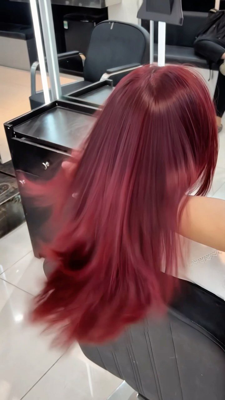 8 Deep Red Hair Dye Ideas for Every Cut and Texture 5 Long, straight, deep red hair flowing over a black salon chair.