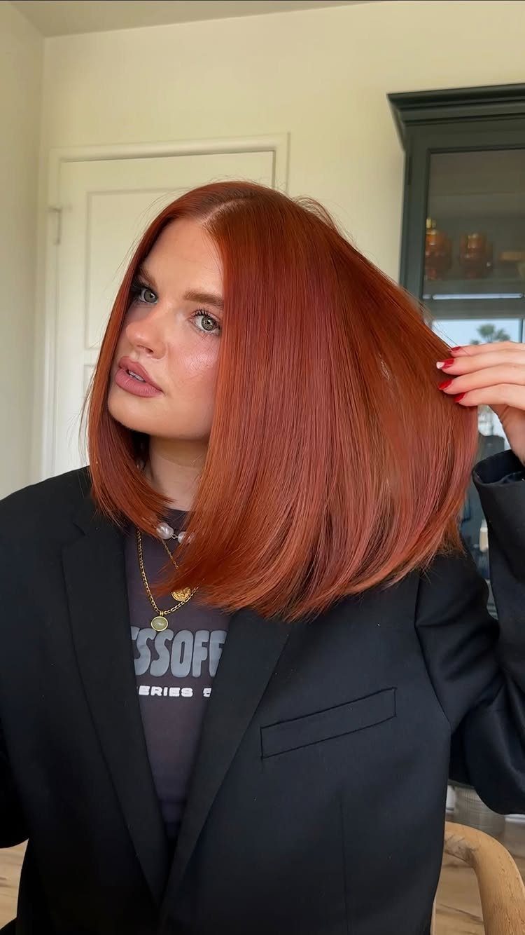 8 Deep Red Hair Dye Ideas for Every Cut and Texture 4 Woman with vibrant deep red bob haircut wearing a black blazer and necklace.
