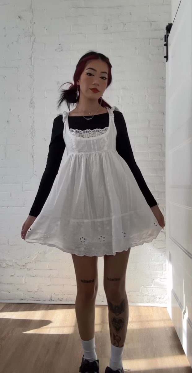 5 Ways to Wear a Dress with Long Sleeves Underneath 4 Person wearing a white babydoll dress over a black long-sleeve top and white socks.