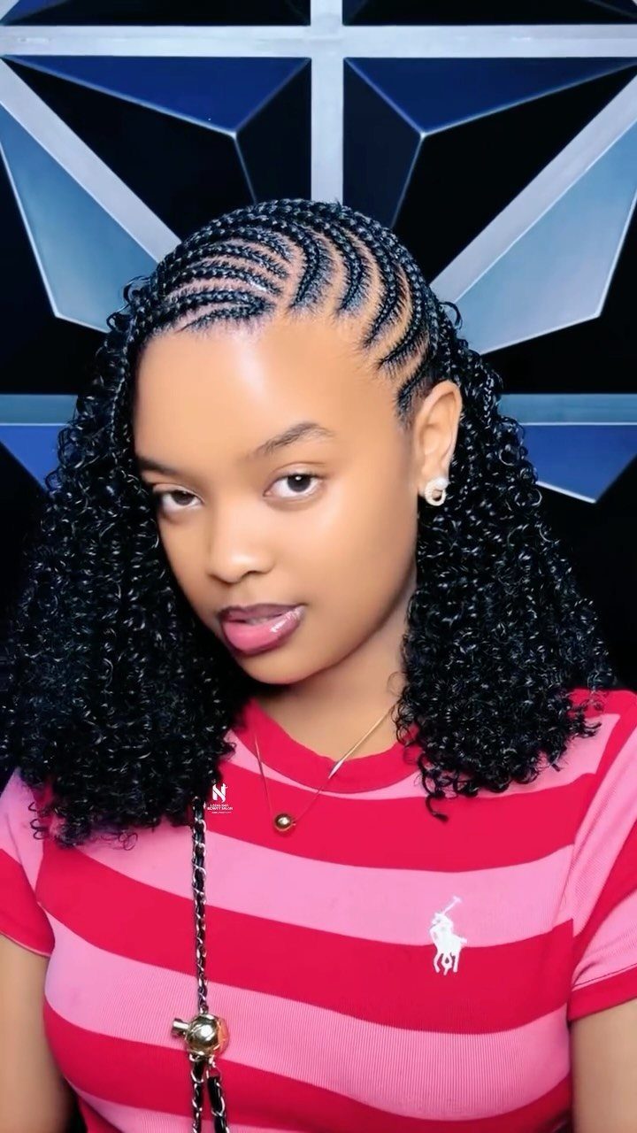 Woman with cornrow braids on top and curly hair wearing striped red shirt.