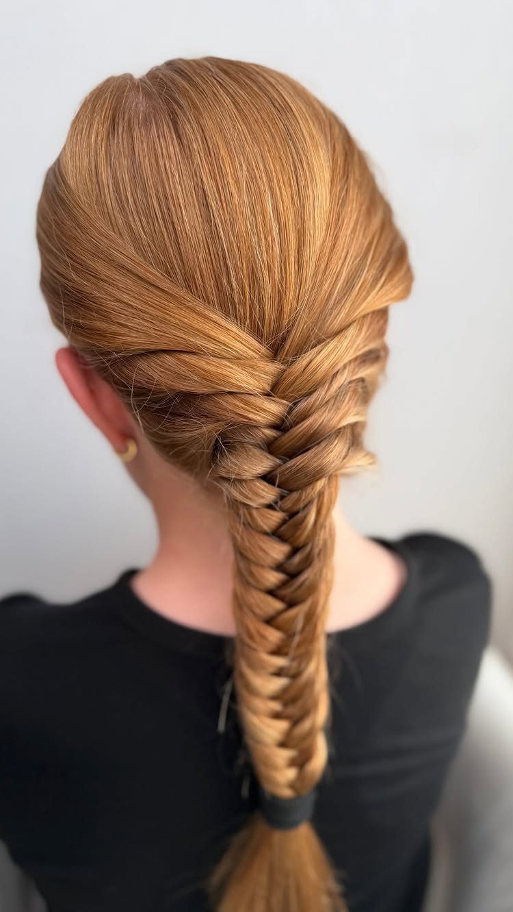 Strawberry blonde hair styled in a long fishtail braid from the back view.
