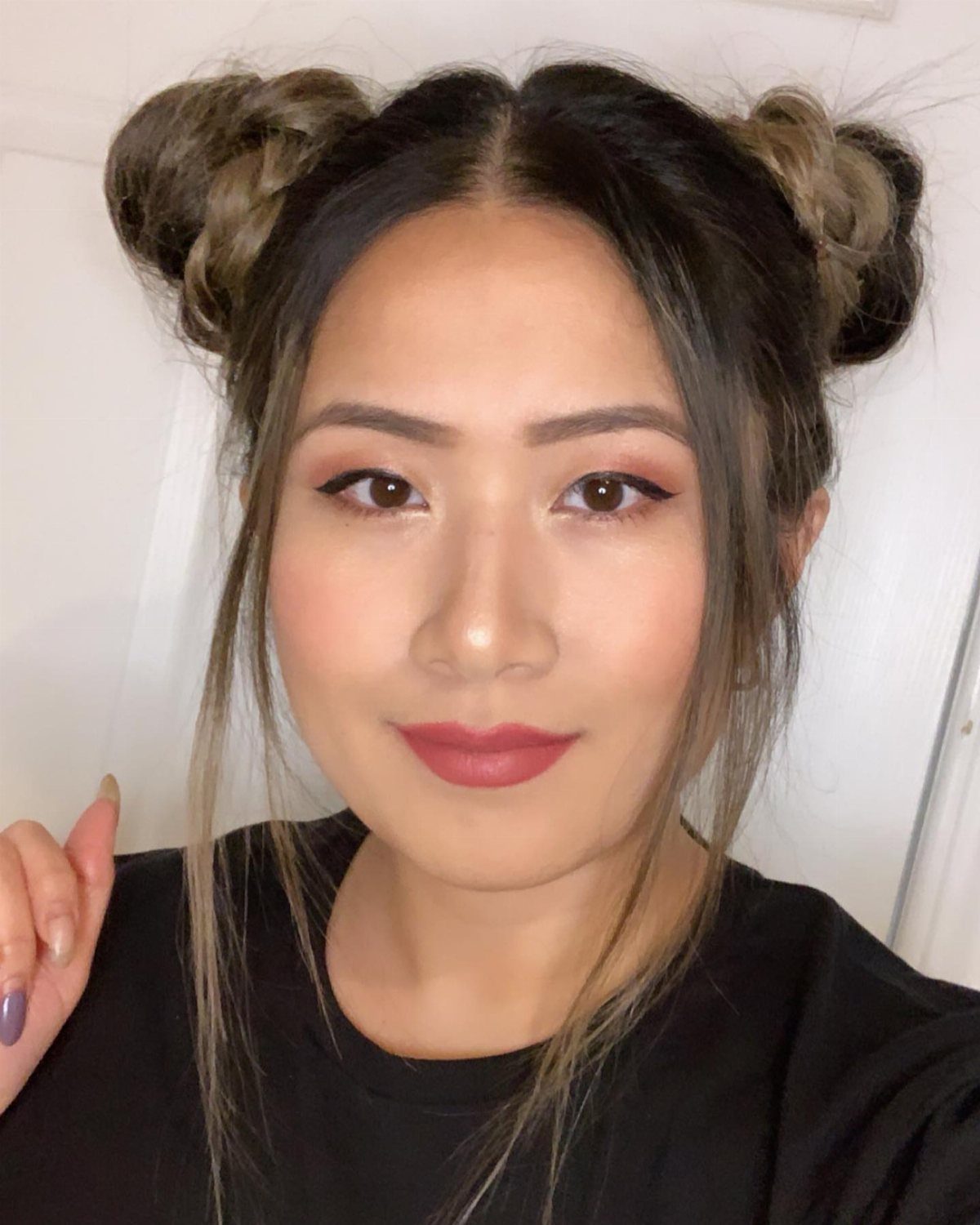 Woman with dark hair styled in two space buns and loose face-framing strands.