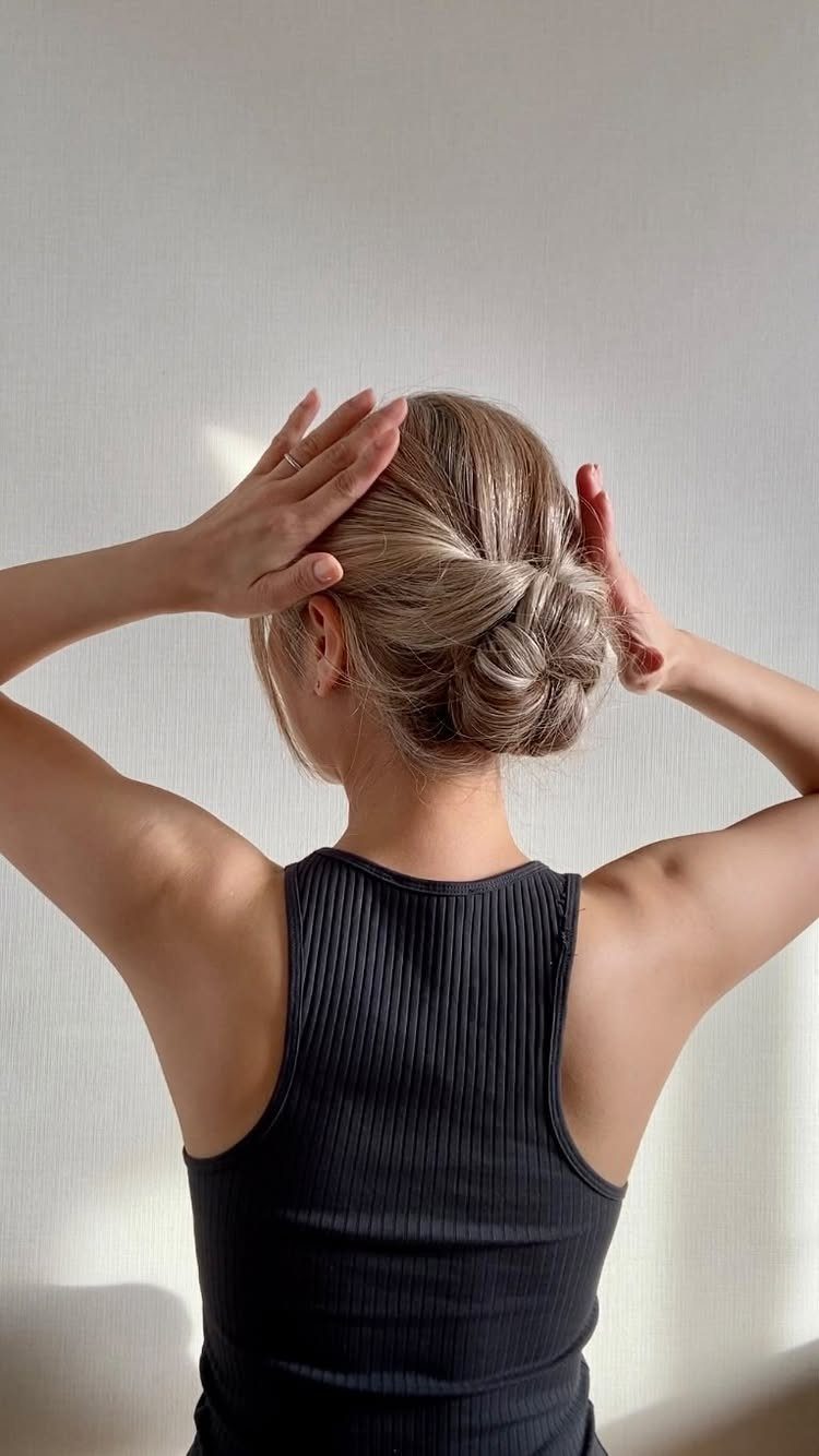 Blonde hair styled into a braided bun at the nape of the neck.