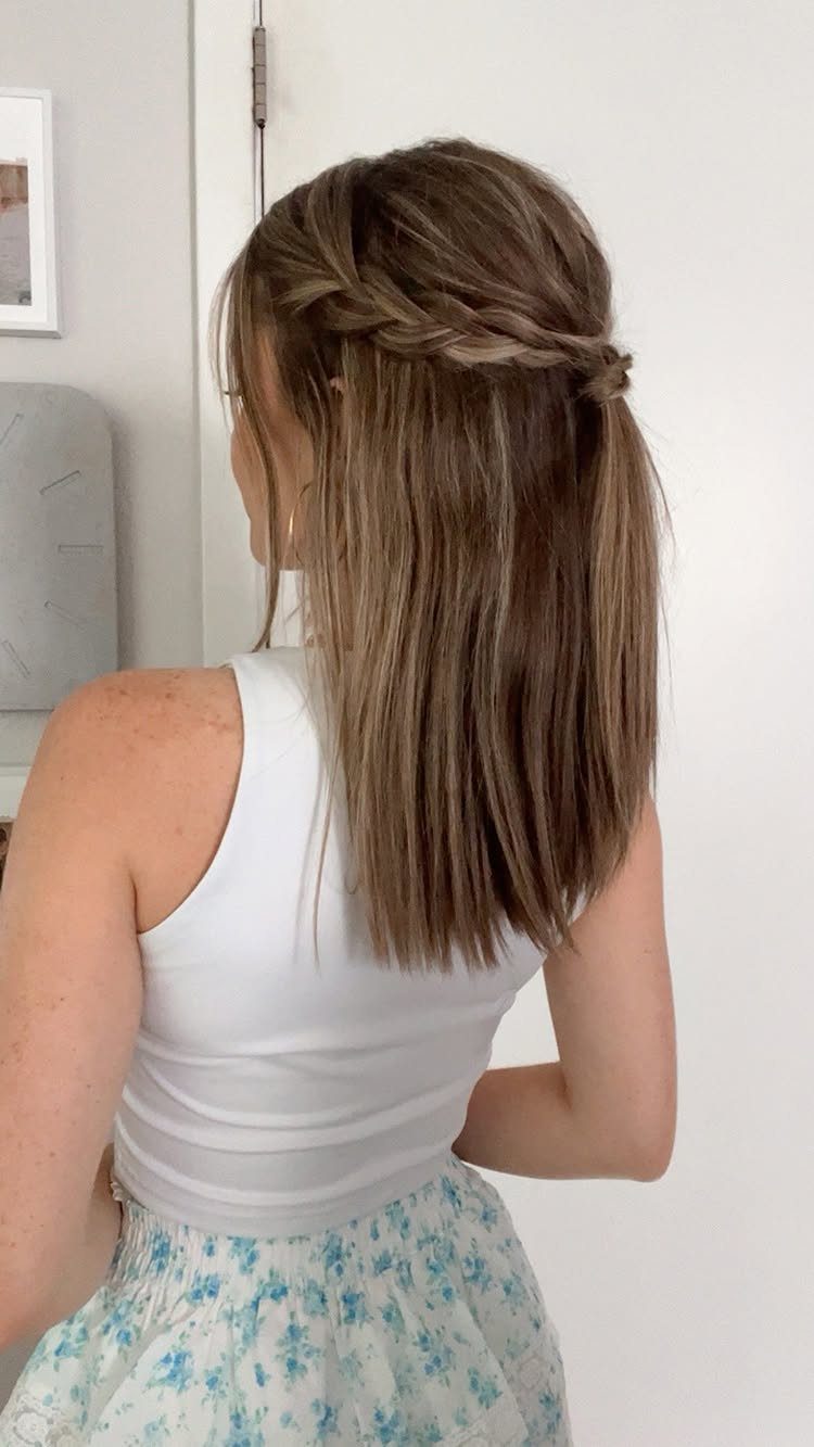 Woman with mid-length brown hair styled in a half-up braided ponytail from behind.