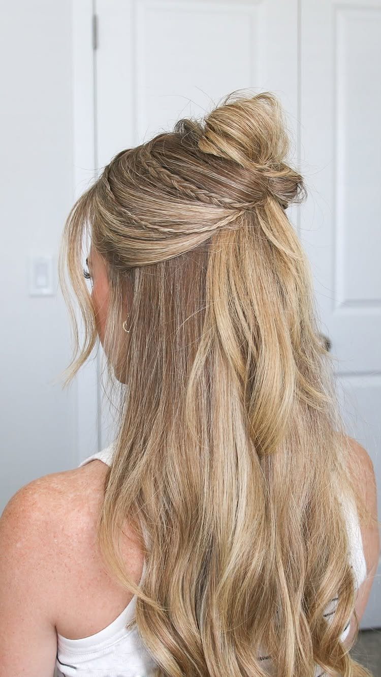 Blonde hair styled in a braided half-up bun with loose wavy lengths.
