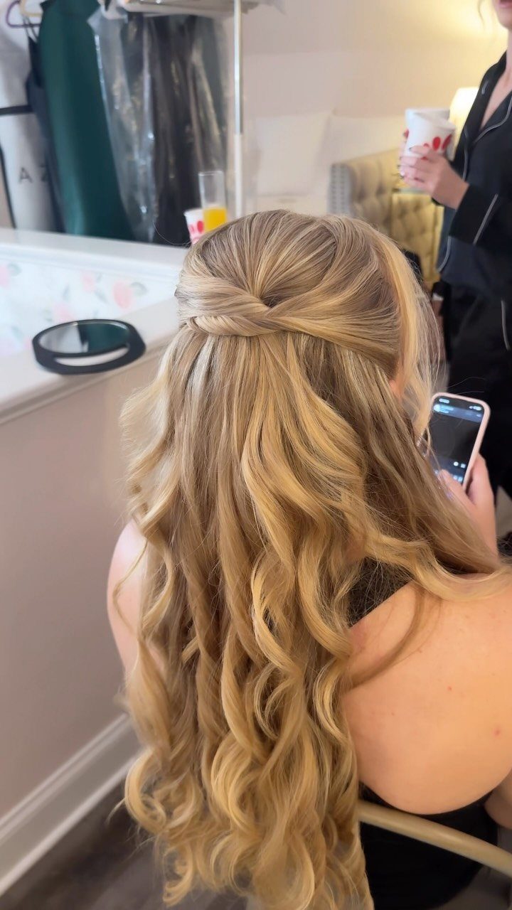 Blonde wavy hair styled in a half-up twist secured at the back.
