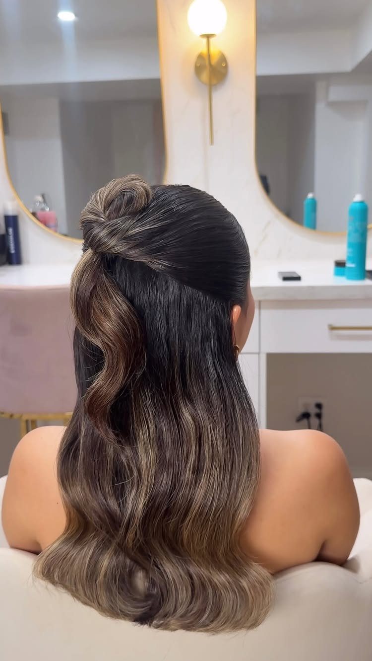 Woman with mid-length brown hair in a half-updo with soft waves from behind