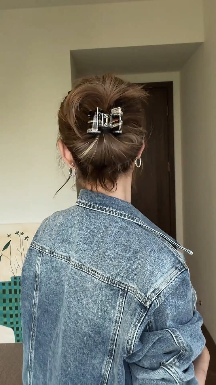 Brown mid-length hair in a messy up-do secured with a silver claw clip.
