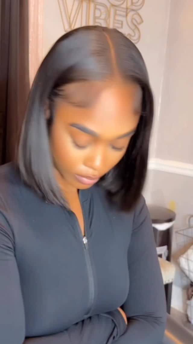 Woman with a sleek, black, middle-parted bob haircut wearing a black zip-up top.