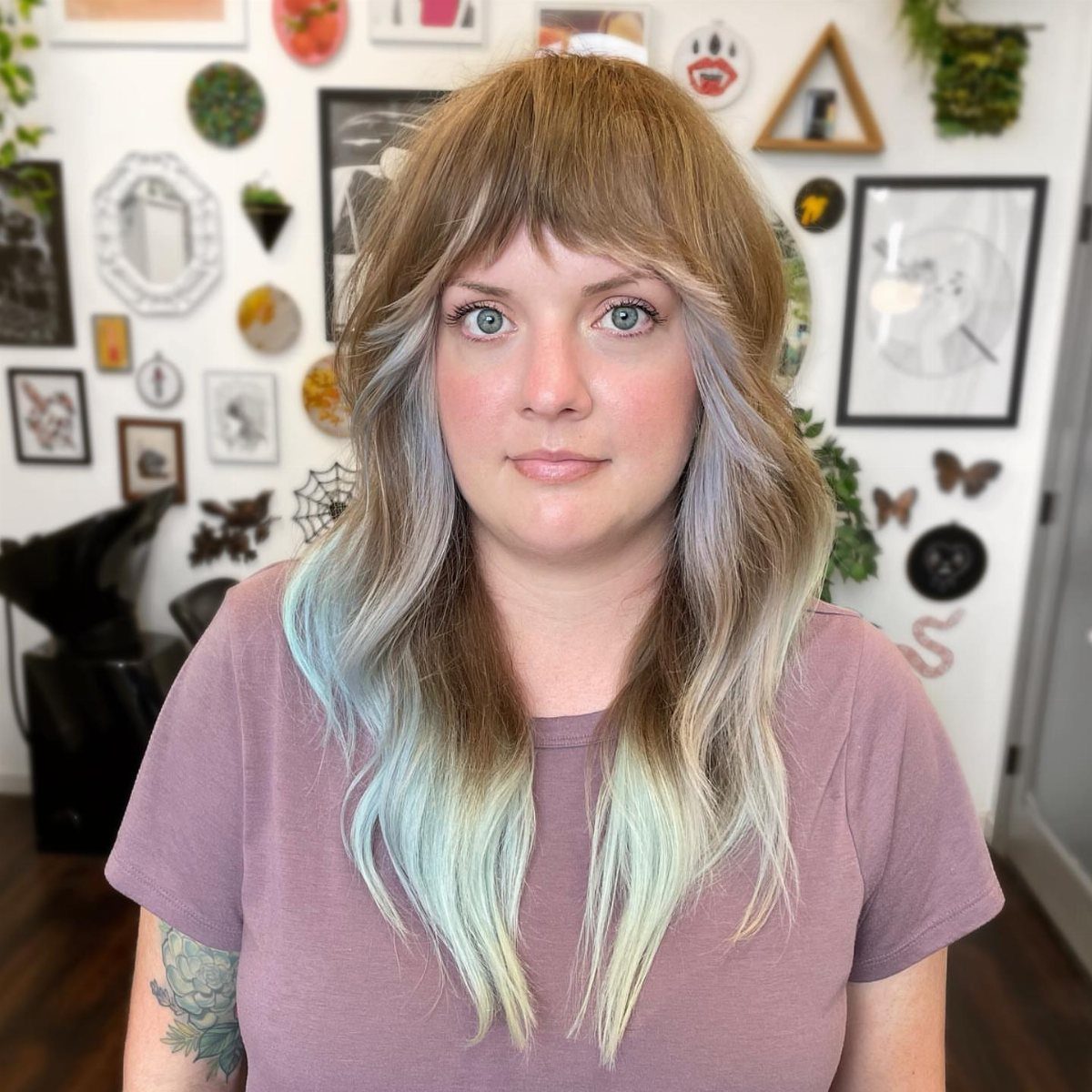 Woman with a layered shag haircut, thick bangs, and blue ombre hair.