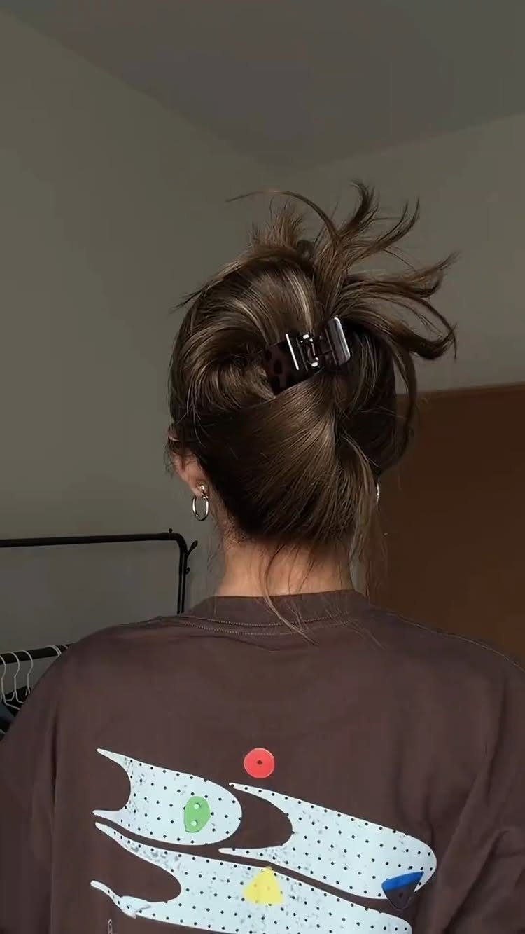 Messy brown hair bun secured with a black claw clip from behind.