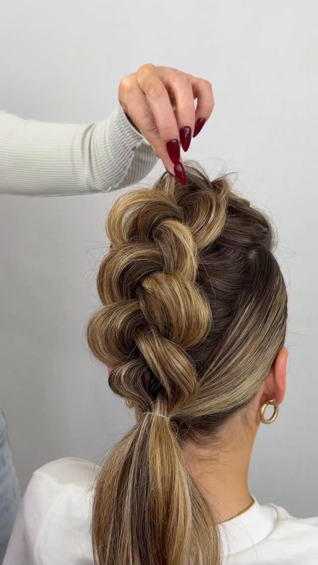 Blonde highlighted hair styled in a thick braid and ponytail from behind