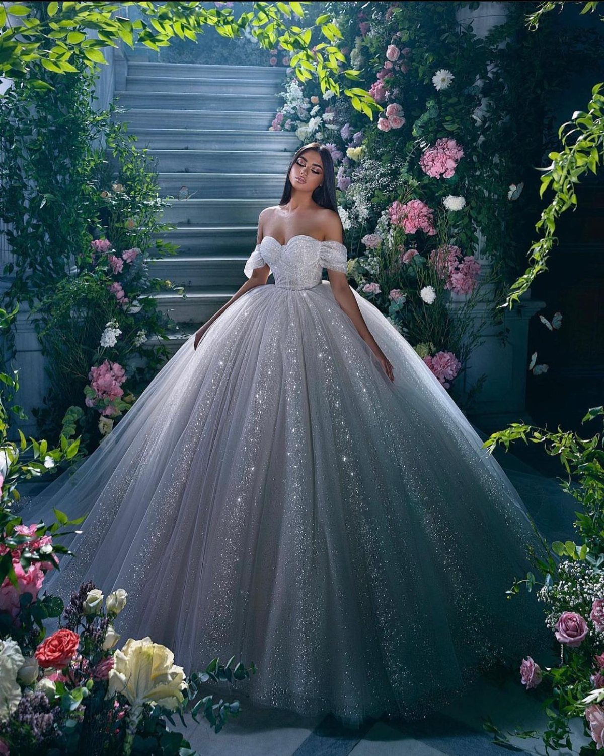 Woman in a sparkling white ball gown wedding dress standing in a floral garden