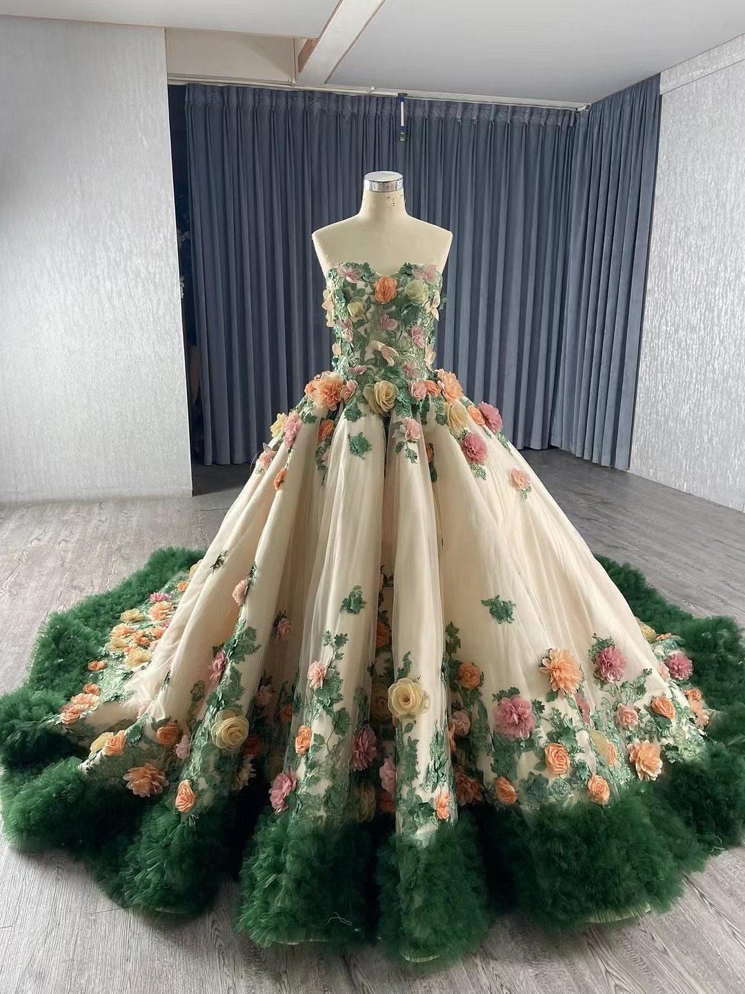 Cream ball gown wedding dress with colorful 3D floral appliqués and green tulle hem.