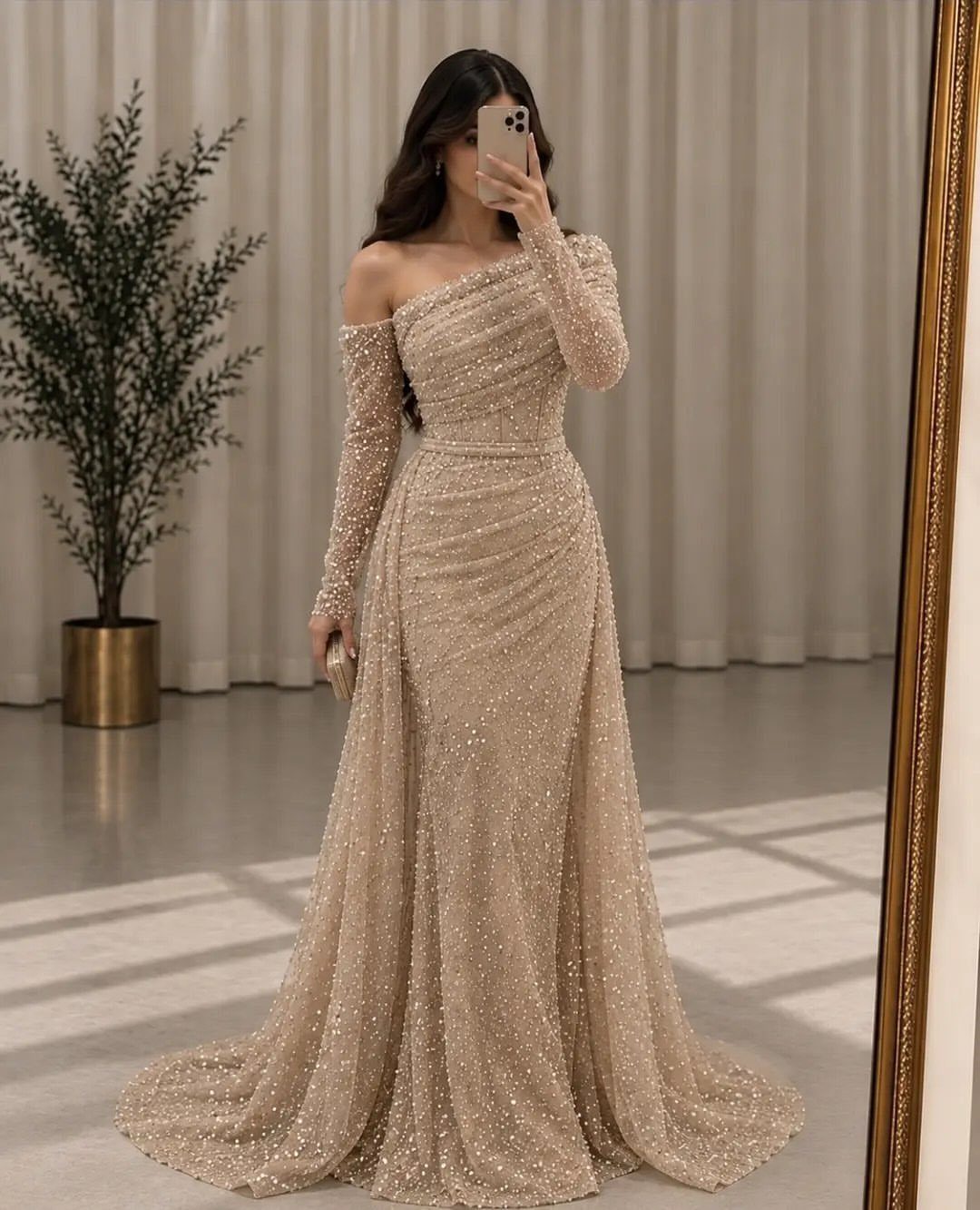 Woman in a shimmering champagne gown with an asymmetrical off-the-shoulder neckline.