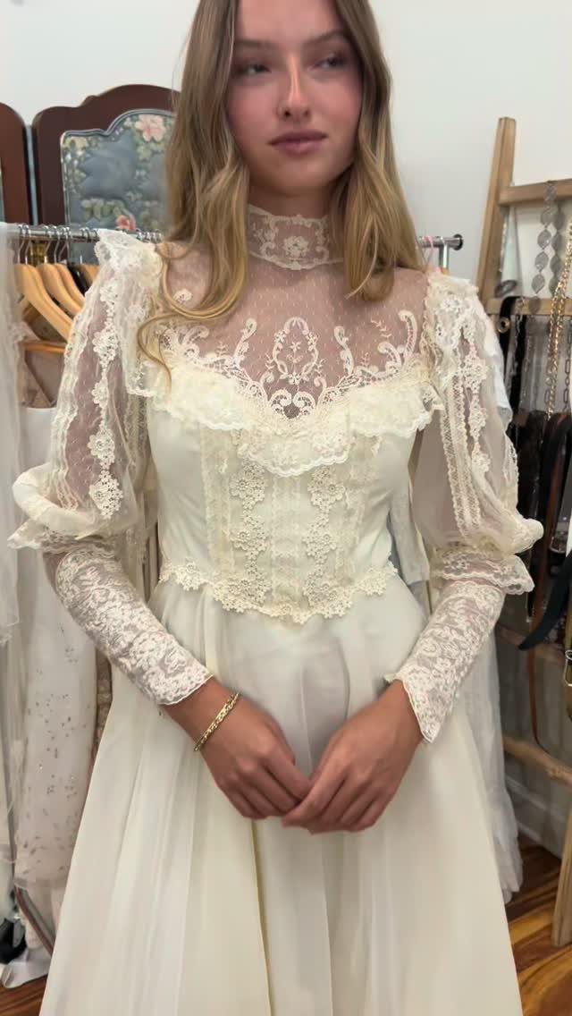 Woman wearing a cream vintage-style wedding dress with intricate lace and corset bodice.