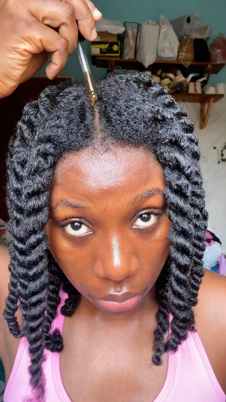 Woman with twisted natural hair receiving a scalp oil treatment with a dropper