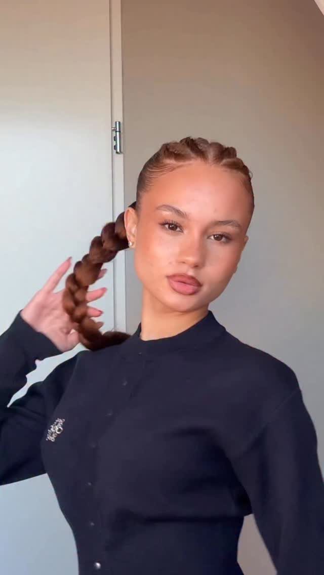 Woman with cornrow braids transitioning into a thick braided ponytail wearing black top